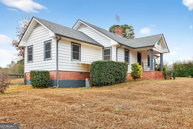 a view of a house with a yard and lawn chairs under an umbrella