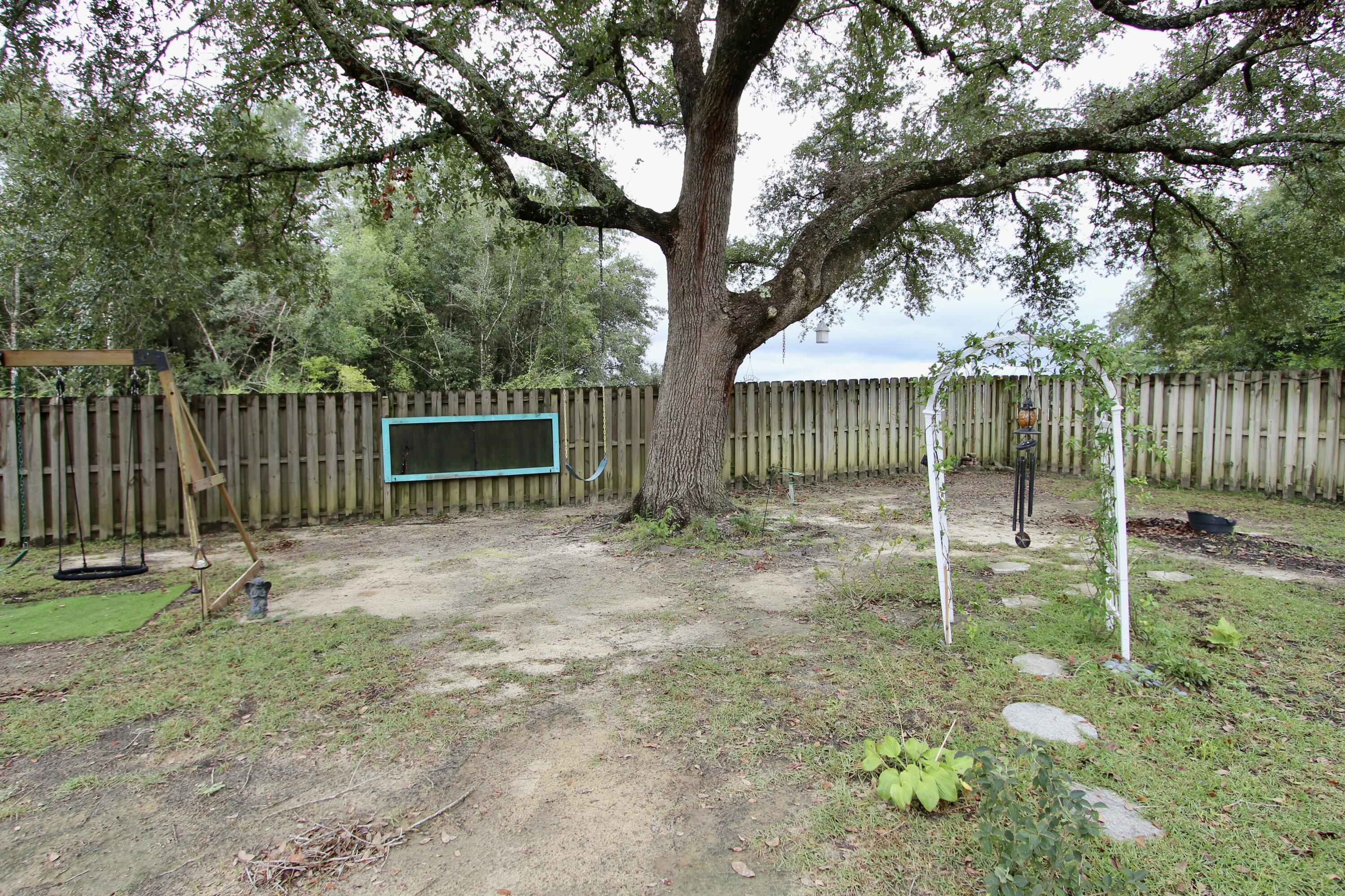 4641 Chanan Drive Crestview, FL 32539 - Photo 43 of 45 a backyard of a house with plants and tree with wooden fence
