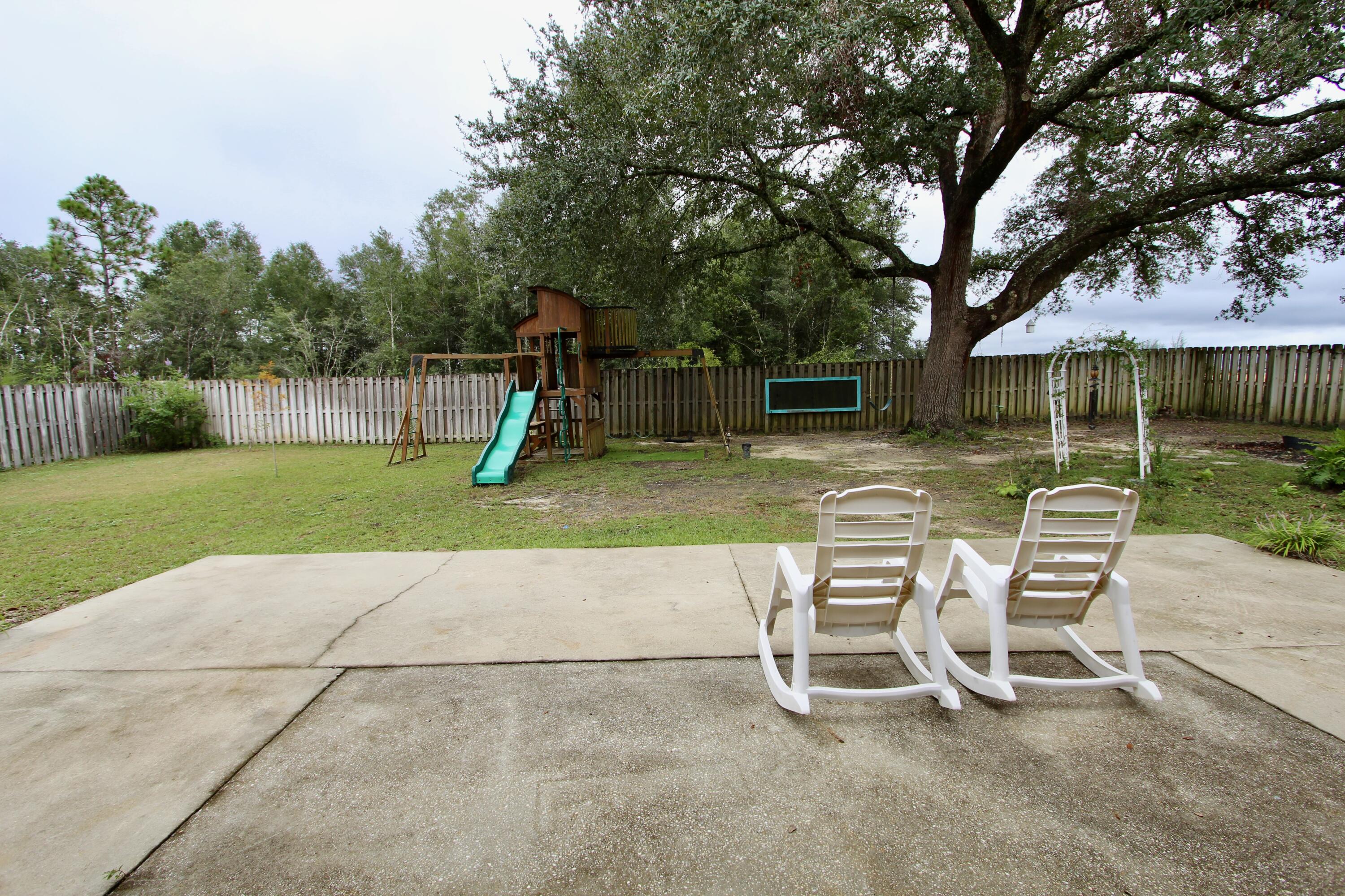 4641 Chanan Drive Crestview, FL 32539 - Photo 45 of 45 a view of a backyard with chairs and a slide