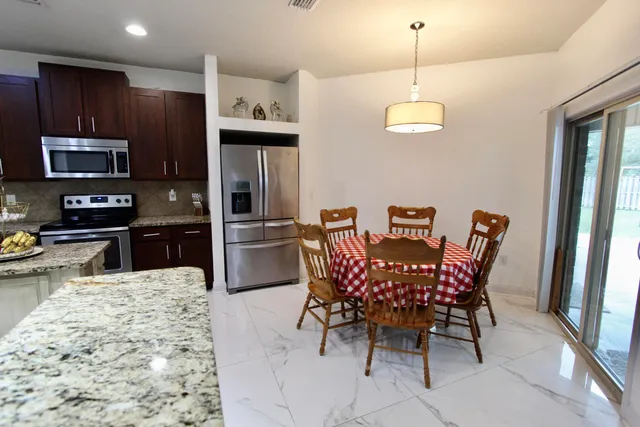 a kitchen with stainless steel appliances granite countertop a dining table and chairs