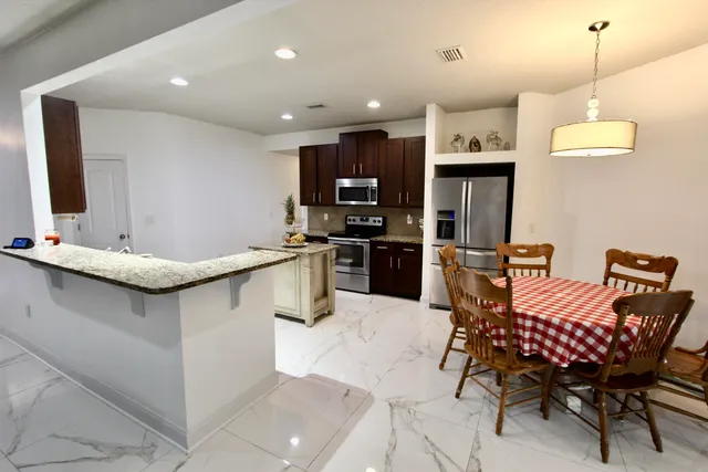 a kitchen with stainless steel appliances kitchen island granite countertop a sink and a refrigerator