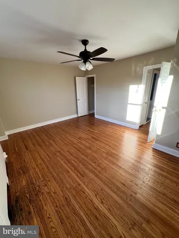 a view of empty room with wooden floor and fan