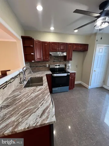 a kitchen with kitchen island granite countertop a sink stove and cabinets