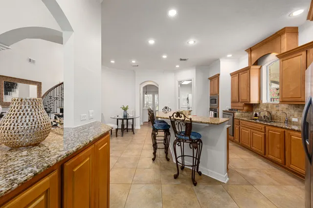 a kitchen with granite countertop kitchen island stainless steel appliances a stove a sink a refrigerator and cabinets