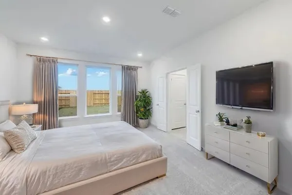a spacious bedroom with a bed and a flat screen tv