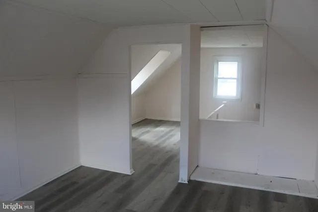 an empty room with wooden floor cabinet and windows