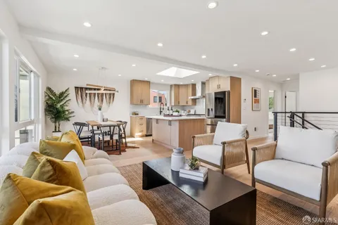 a living room with furniture wooden floor and a kitchen view