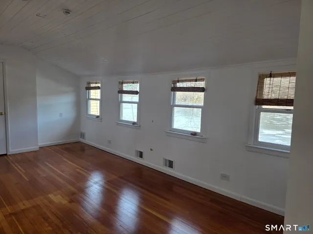 a view of an empty room with wooden floor and closet