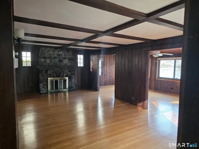 a view of an empty room with window chandelier and wooden floor