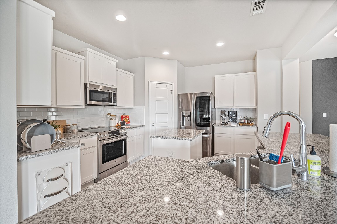 9905 Comely Bend Manor, TX 78653 - Photo 12 of 22 Kitchen with white cabinetry, stainless steel appliances, light stone countertops, recessed lighting, and backsplash