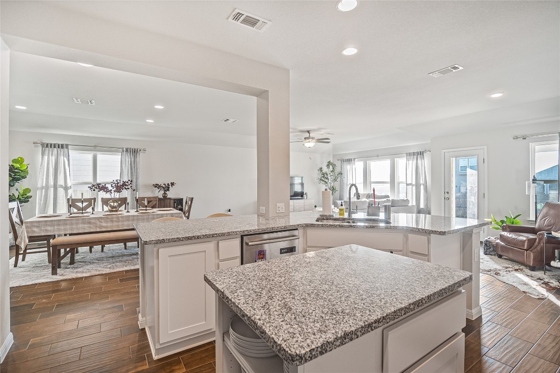 9905 Comely Bend Manor, TX 78653 - Photo 22 of 22 Kitchen with open floor plan, wood finish floors, light stone counters, white cabinetry, and plenty of natural light