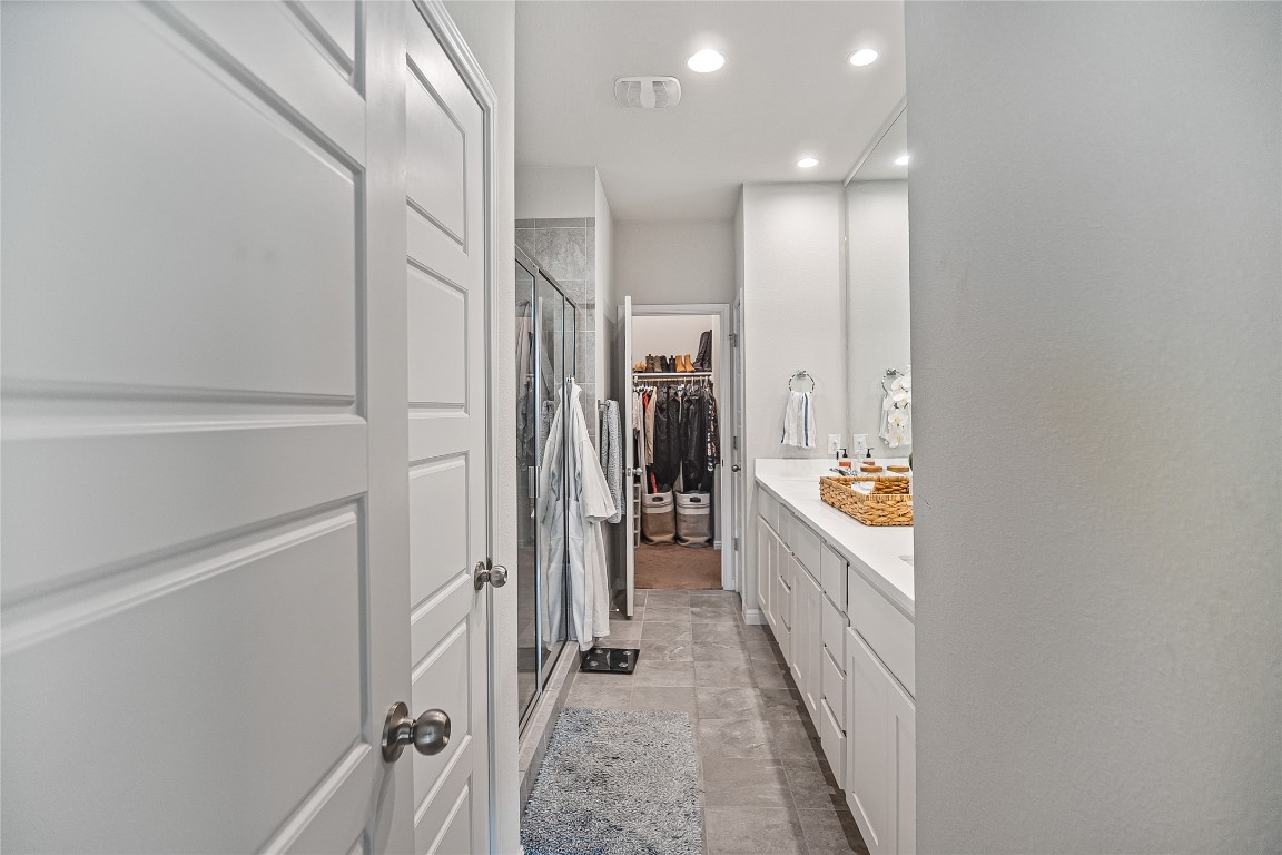 9905 Comely Bend Manor, TX 78653 - Photo 15 of 22 Bathroom featuring vanity, a stall shower, a walk in closet, and recessed lighting