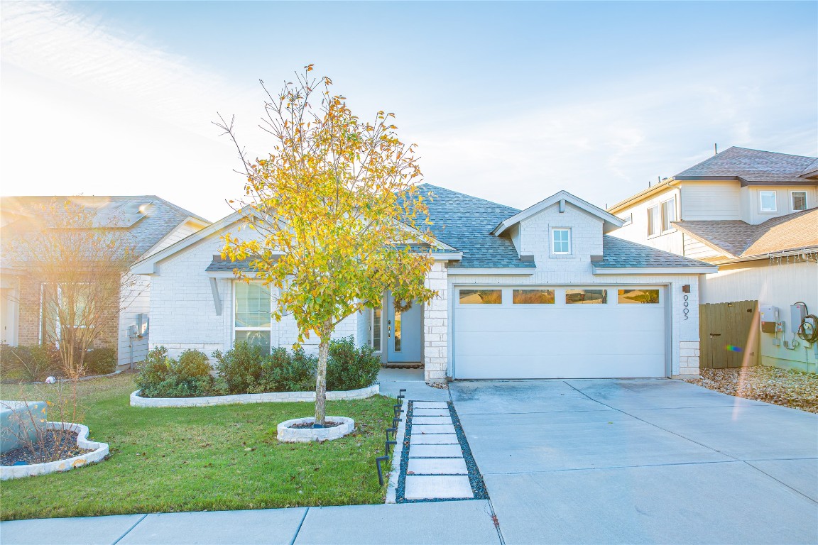 9905 Comely Bend Manor, TX 78653 - Photo 2 of 22 View of front of house with a front yard, a shingled roof, driveway, and an attached garage