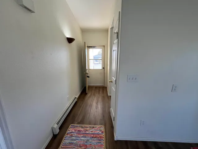 a view of a hallway with wooden floor and a bathroom