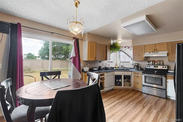 a kitchen with stainless steel appliances granite countertop a stove a sink dishwasher a dining table and chairs with wooden floor