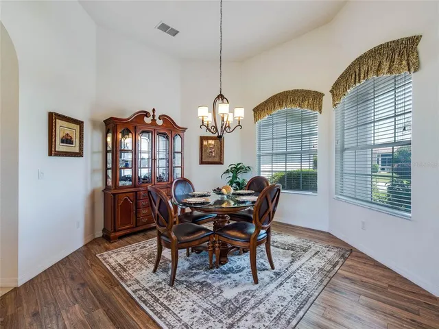 a dining room with furniture a chandelier and wooden floor