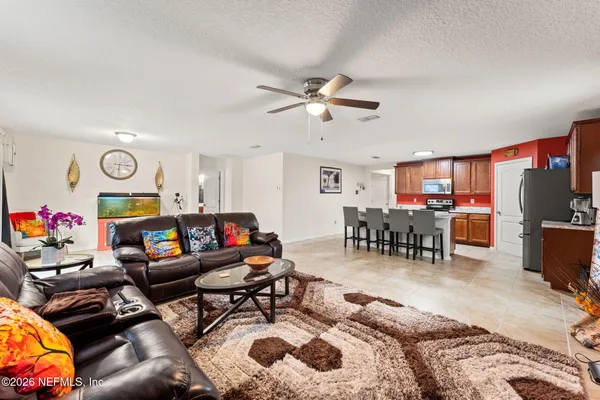 a living room with furniture and a flat screen tv with kitchen view