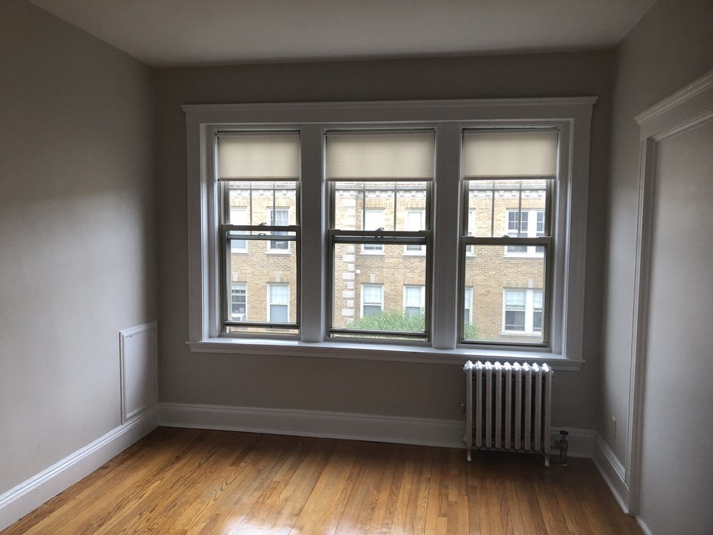 11 Perkins Square, Unit 11 Boston, MA 02130 - Photo 2 of 12 an empty room with wooden floor and windows