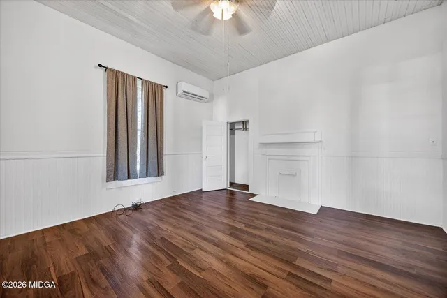 a view of an empty room with a window and wooden floor
