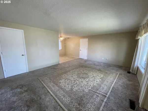 a view of an empty room with a ceiling fan and window