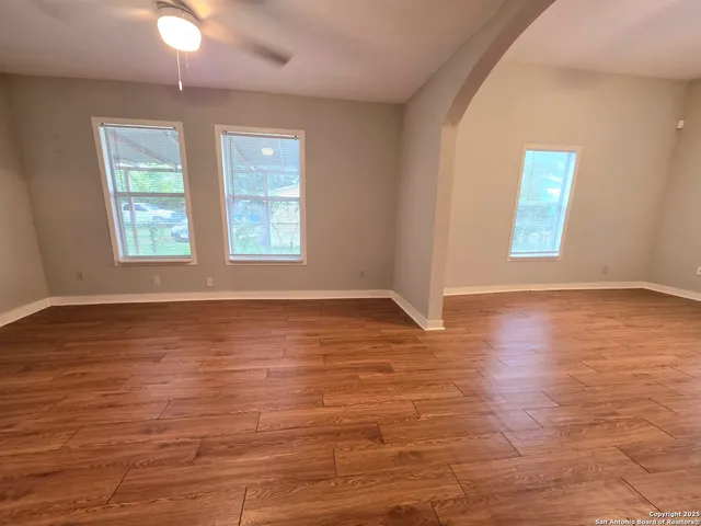an empty room with wooden floor and windows