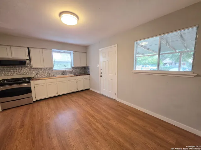 a kitchen with a wooden floor and white stainless steel appliances