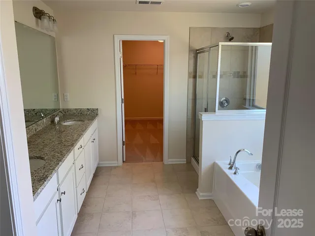 a bathroom with a granite countertop tub sink and mirror