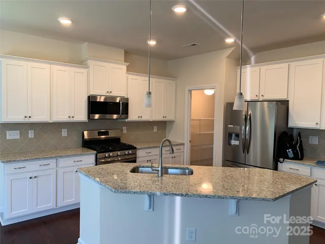 a kitchen with stainless steel appliances granite countertop a sink refrigerator and microwave