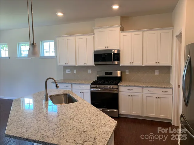 a kitchen with stainless steel appliances granite countertop a sink a stove and a refrigerator