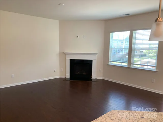 an empty room with wooden floor fireplace and windows