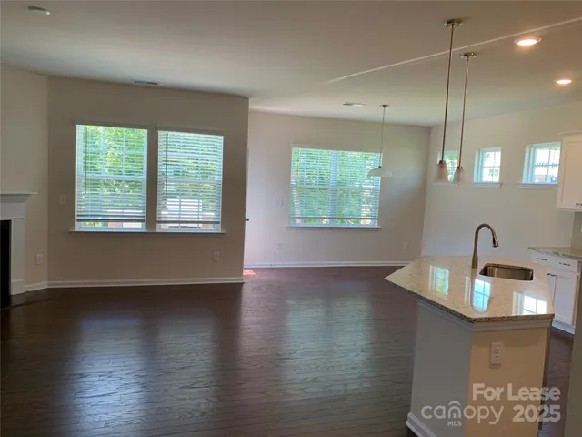 a kitchen with stainless steel appliances granite countertop a sink a stove a dining table and chairs with wooden floor