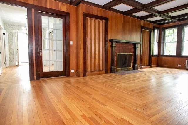 an empty room with windows fireplace and wooden floor
