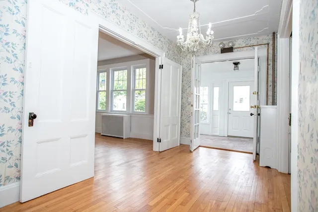 a view of a hallway with wooden floor and a chandelier