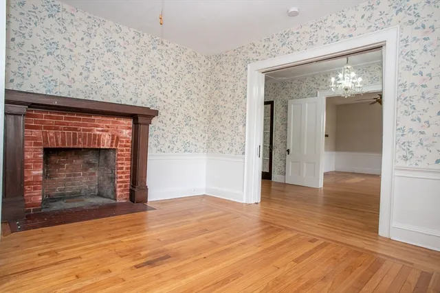 a view of empty room with wooden floor and fireplace