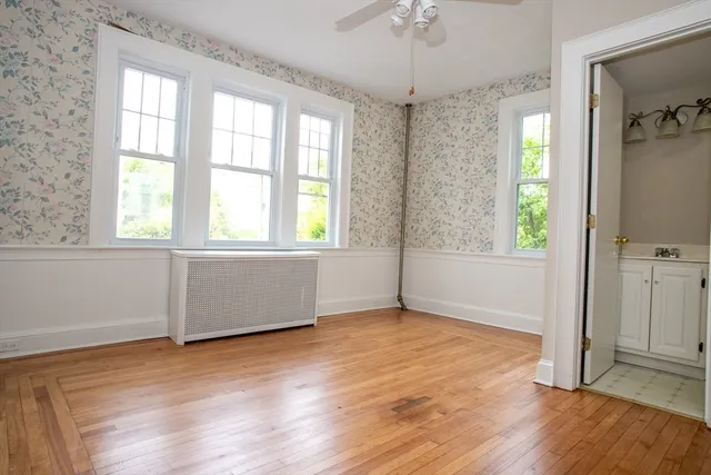 a view of an empty room with a window and wooden floor
