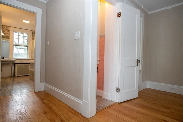 a view of a hallway with wooden floor and a bathroom