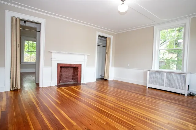a view of empty room with wooden floor and fireplace