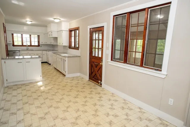 a large white kitchen with granite countertop a sink window and stainless steel appliances