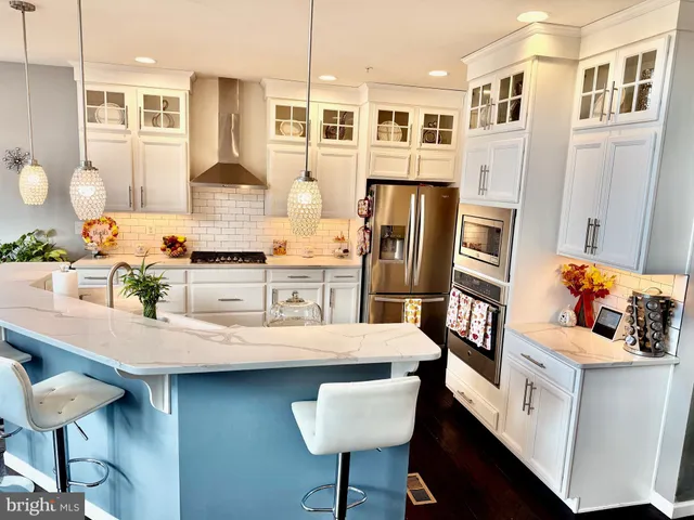 a kitchen with stainless steel appliances kitchen island granite countertop a table chairs and a refrigerator
