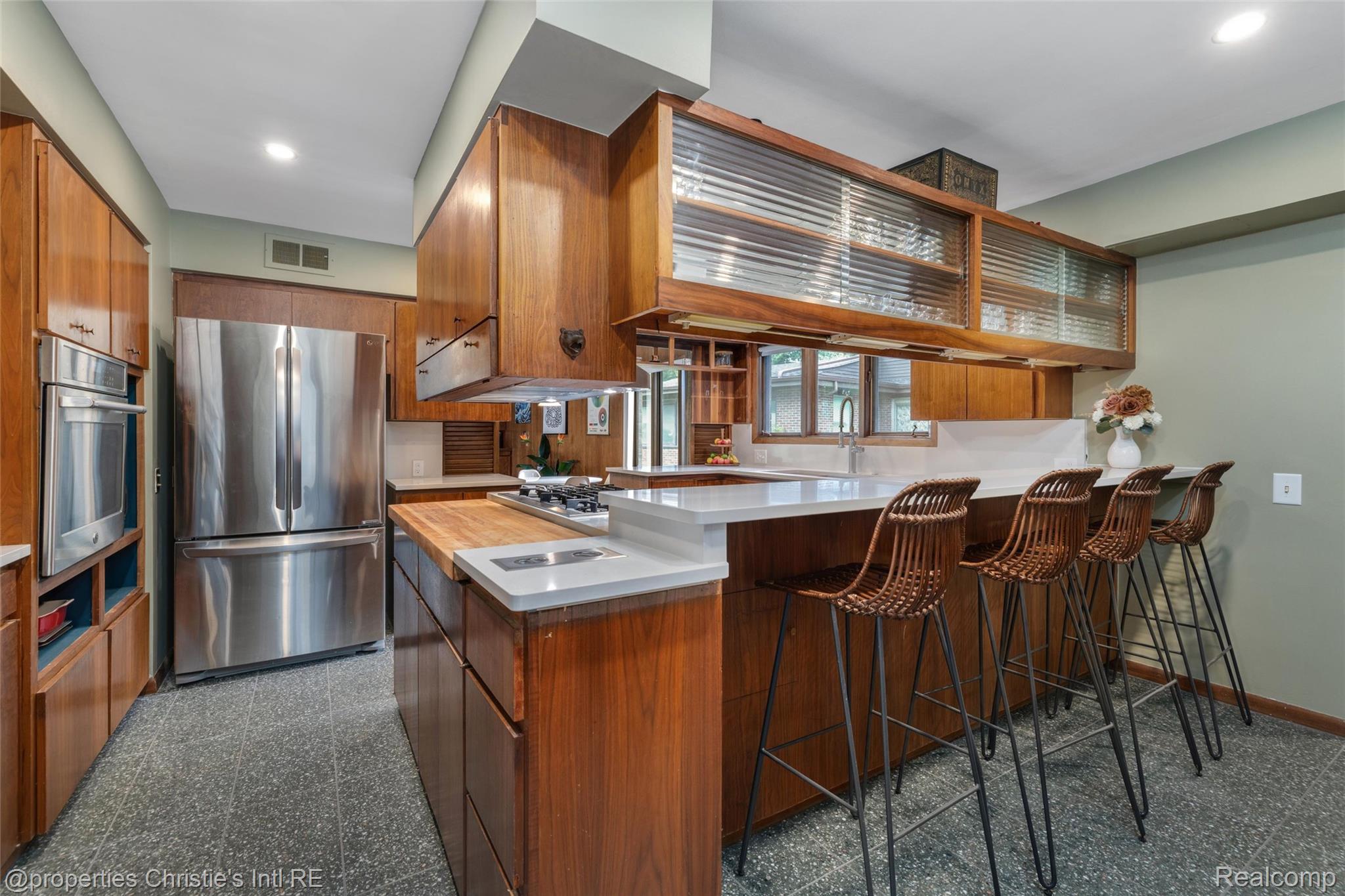 2771 West Seven Mile Road Detroit, MI 48221 - Photo 16 of 57 Kitchen featuring wood cabinetry, stainless steel appliances, a white countertop island with seating, and integrated cooktop