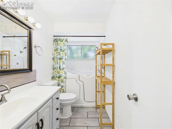 a bathroom with a granite countertop sink a toilet and shower