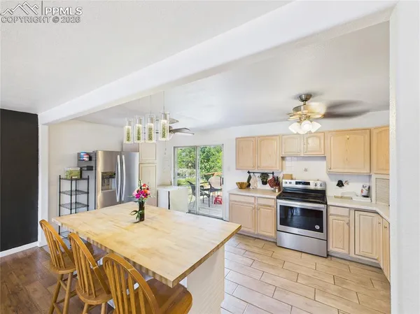a kitchen with stainless steel appliances kitchen island granite countertop a stove a sink dishwasher and a refrigerator with wooden floor