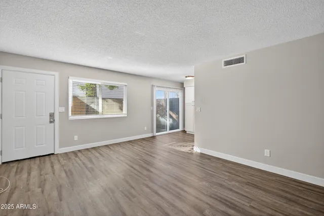 an empty room with wooden floor and windows