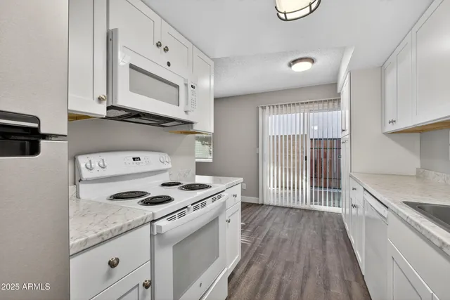 a kitchen with granite countertop white cabinets and white appliances