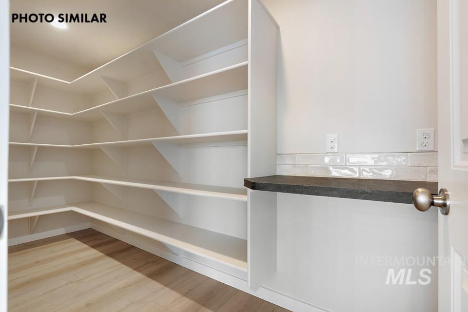 1645 Haystack Emmett, ID 83617 - Photo 13 of 33 Walk-in pantry featuring extensive white shelving, wood-finish flooring, a dark countertop, and a white subway tile backsplash