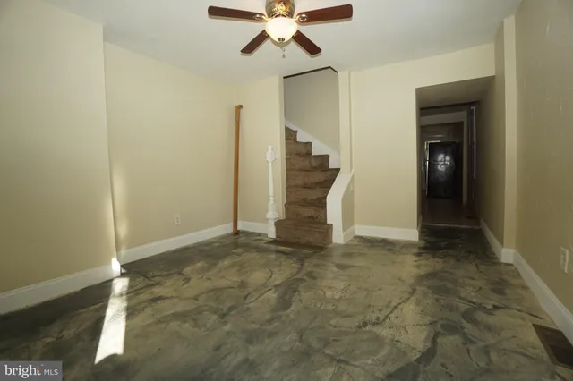 a view of an empty room with closet and a ceiling fan