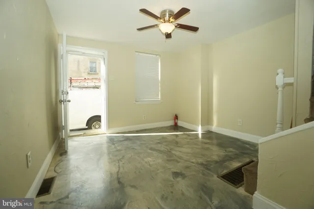a view of an empty room and window with a kitchen