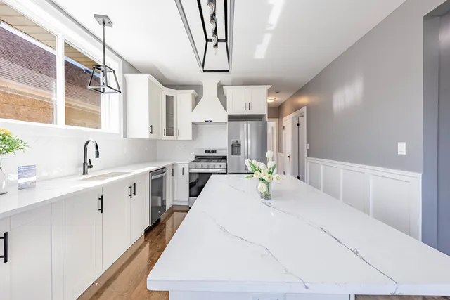a large white kitchen with stainless steel appliances sink stove and cabinets