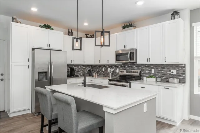 a kitchen with stainless steel appliances a sink a stove a center island and cabinets