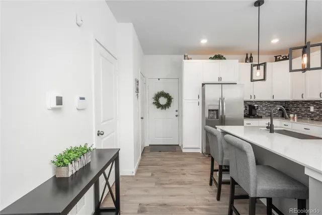 a kitchen with stainless steel appliances a refrigerator a sink a stove and white cabinets